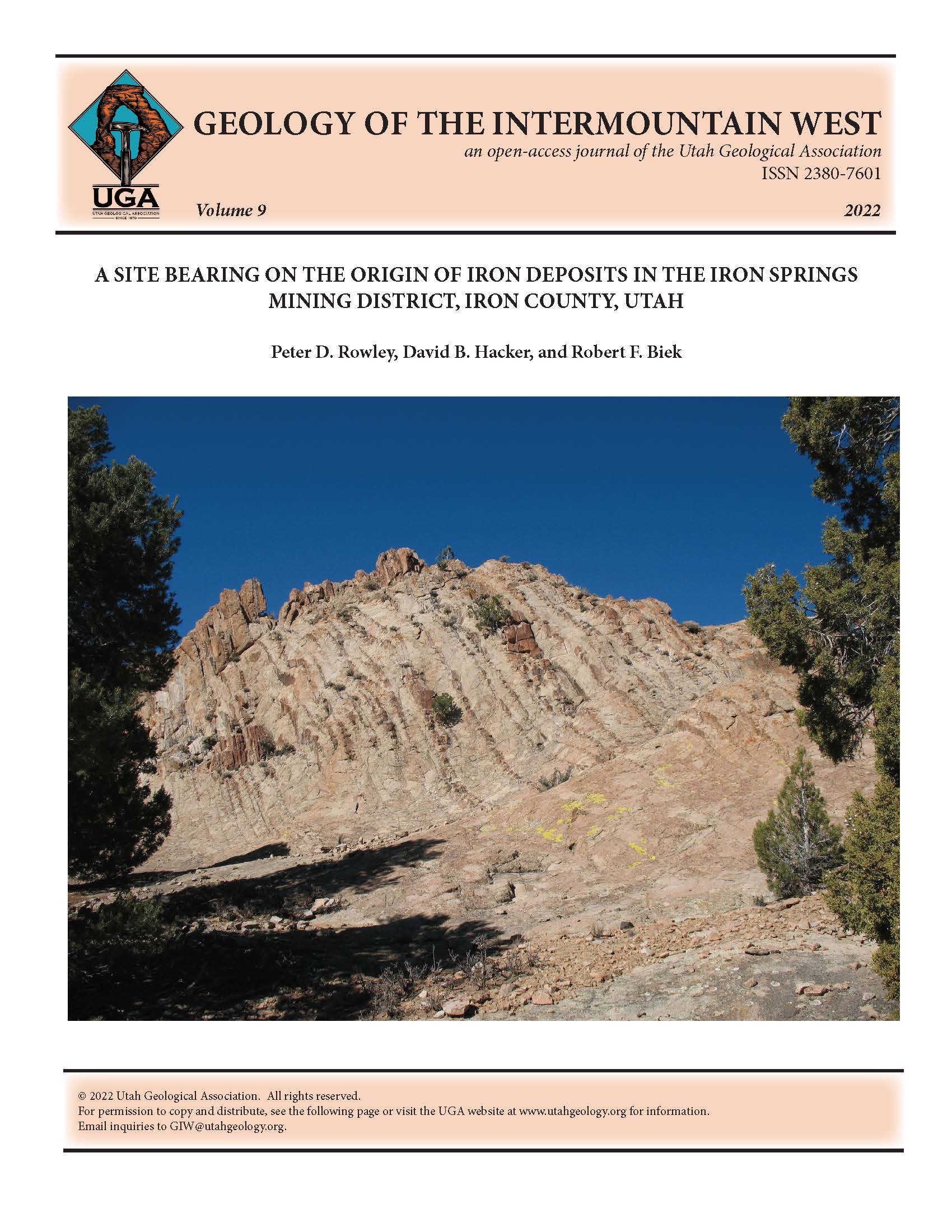 View west at the geosite, within the selvage-joint phase of The Three Peaks intrusion. For scale, a rock hammer is near the base of the cliff, left of center and above the shadows on the left.